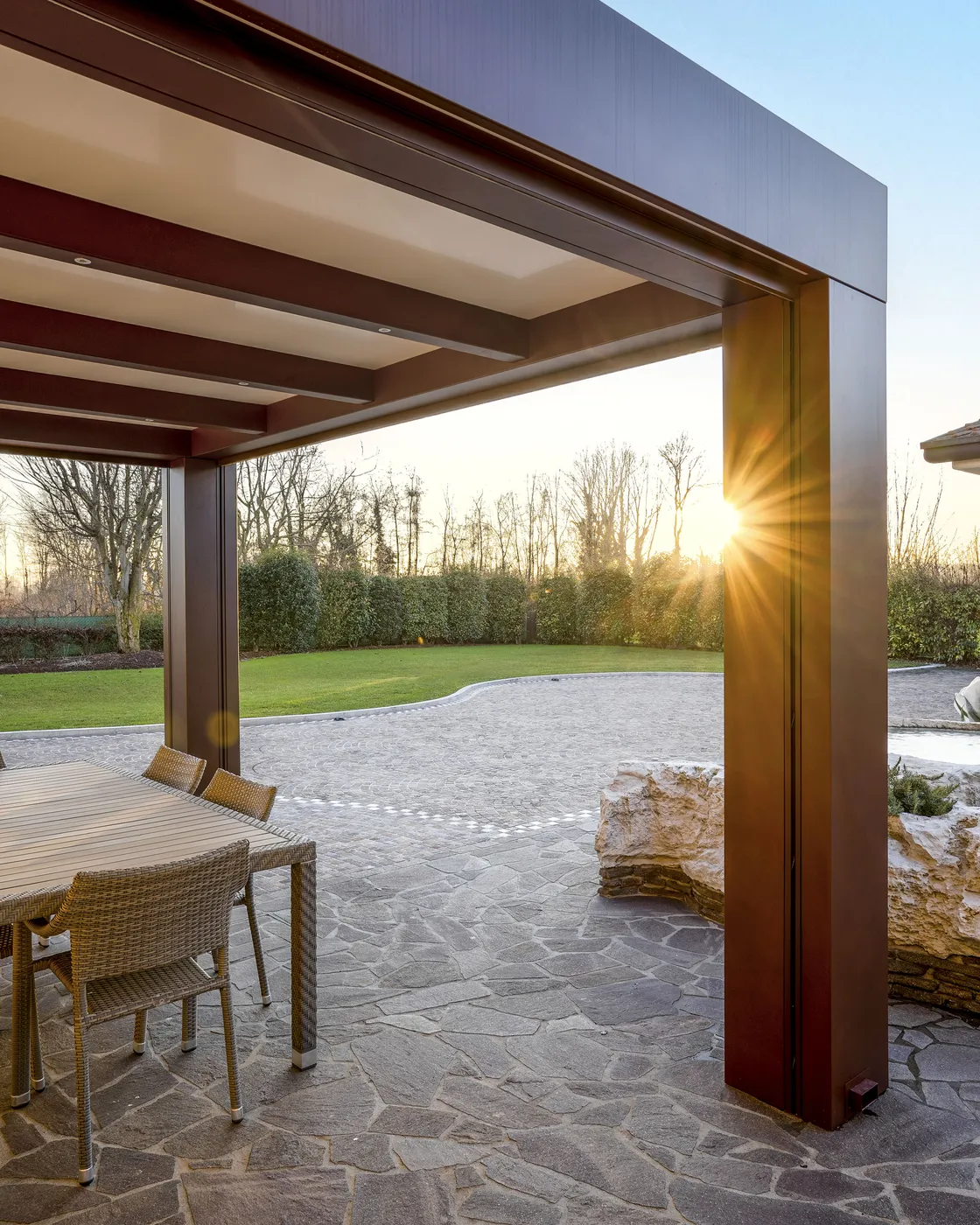 Pergola in legno e alluminio su un patio in pietra al tramonto