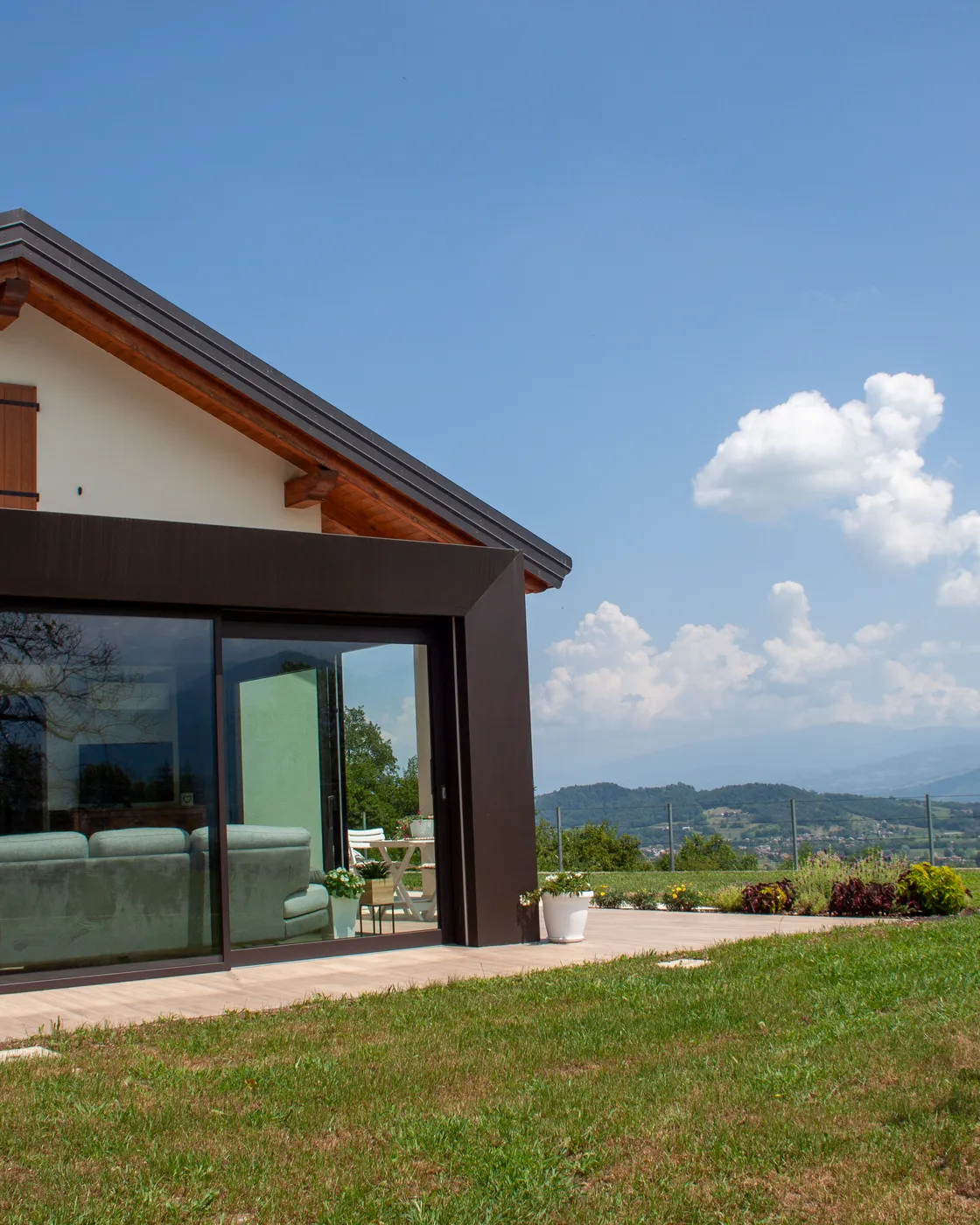 Veranda scura con vetrate scorrevoli affacciata sulle colline